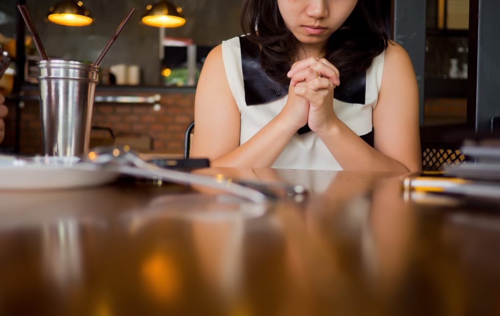 Woman praying at table in kitchen. Third Step of Submitting to God: Prayer