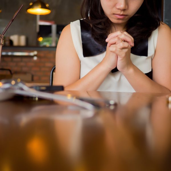 Woman praying at table in kitchen. Third Step of Submitting to God: Prayer