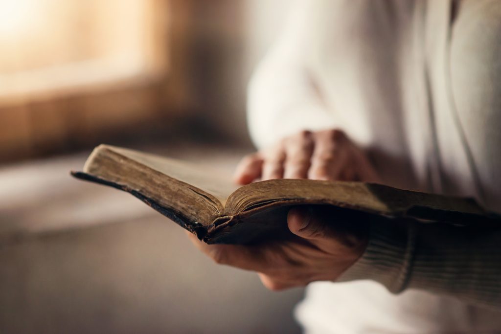 woman's hand on Bible while reading. How to Draw Closer to God by Reading His Word