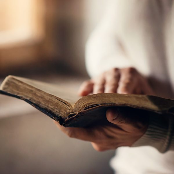 woman's hand on Bible while reading. How to Draw Closer to God by Reading His Word