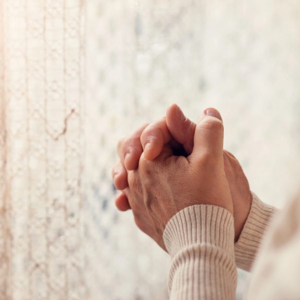 woman's hands praying by window. Standing on God's Promises in Prayer