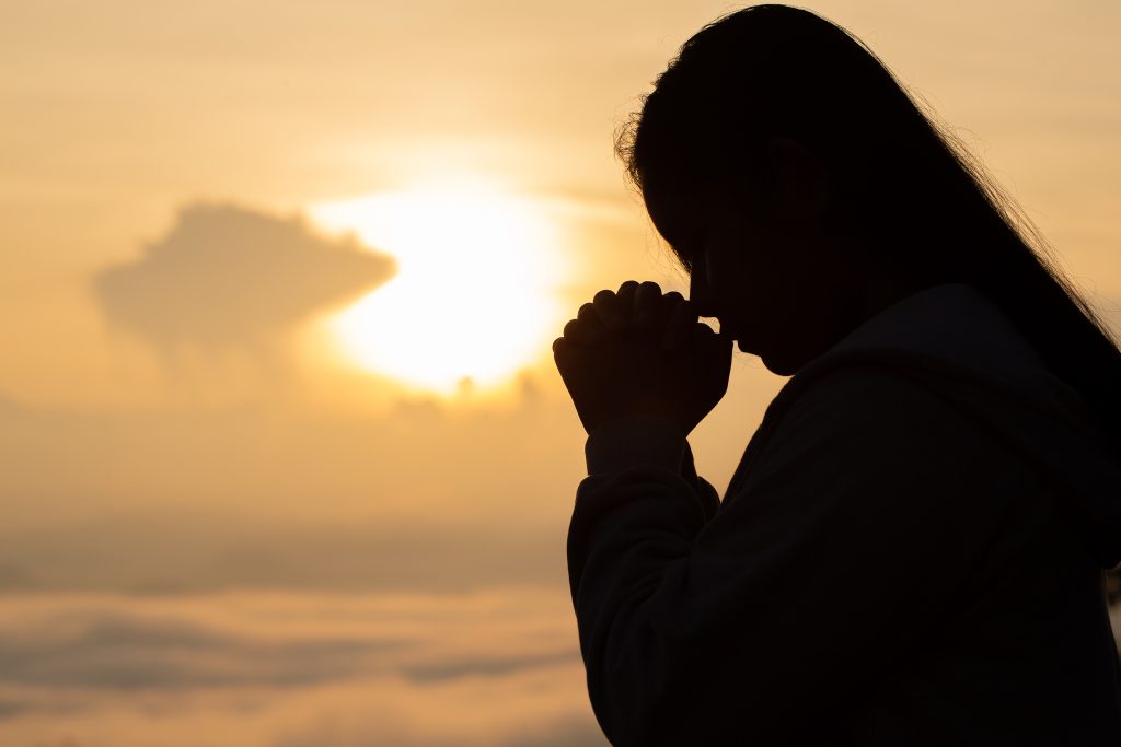 woman in shadow prayer in front of beach. Letting Go abd Trusting God: What Surrender Really Looks Like