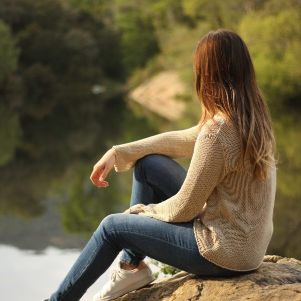 A woman by a lake peacefully looking out over the water. Finding God's peace in uncertain times