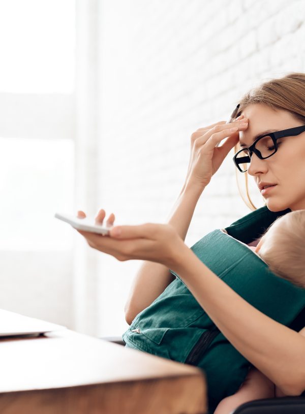Woman with sleeping baby at computer-worn out. Finding strength in God when you feel weak and worn out