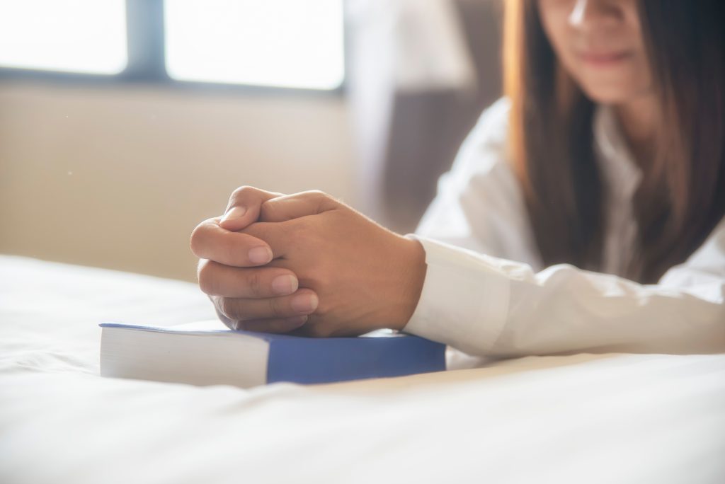 woman kneeling in prayer with Bible.  5 ways to build courage from god’s word for life’s daily battles