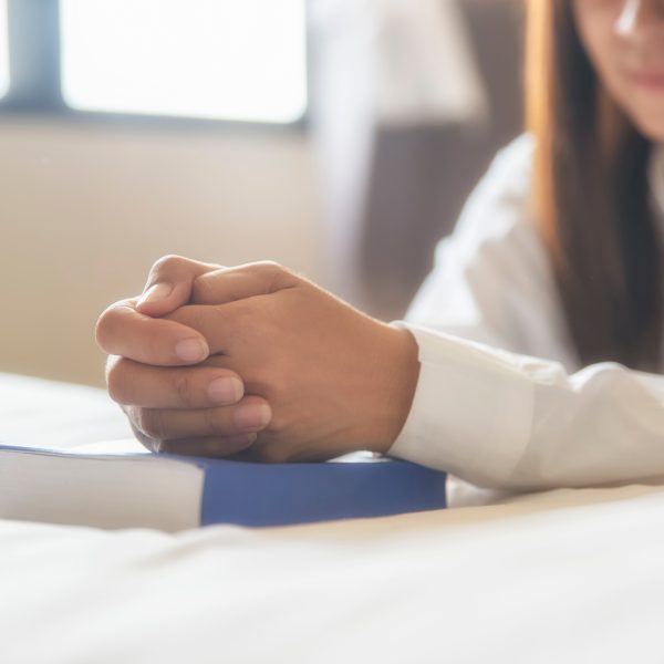 woman kneeling in prayer with Bible. 5 ways to build courage from god’s word for life’s daily battles