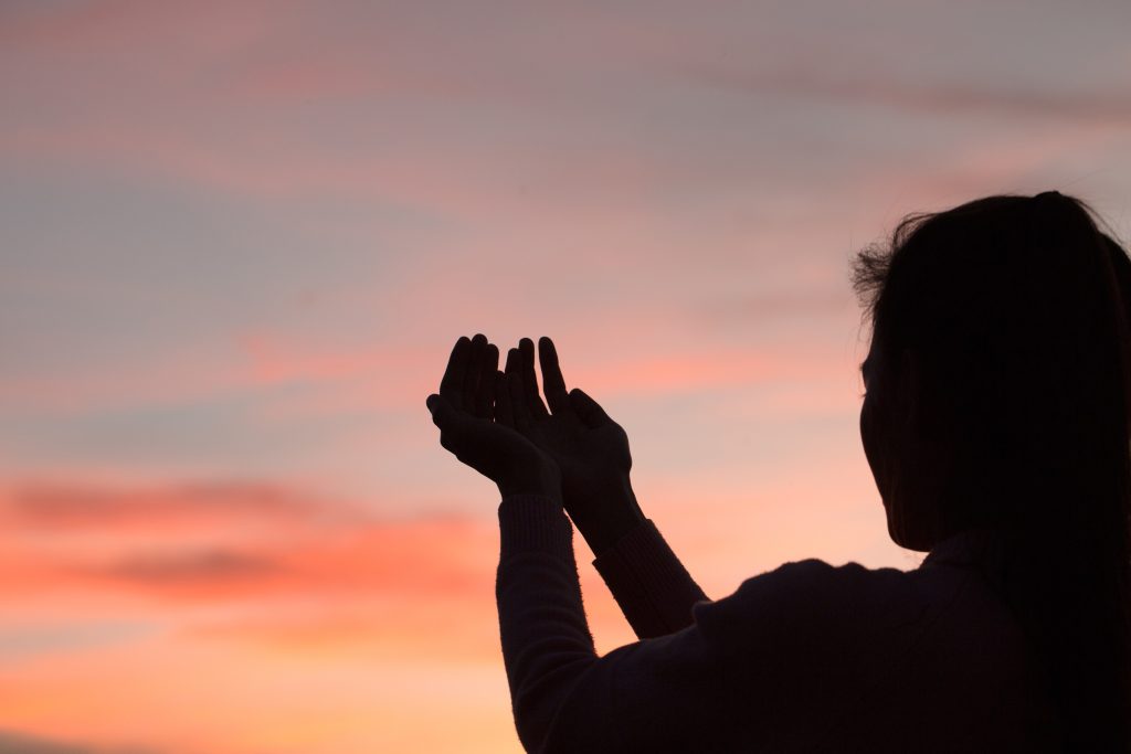 woman in evening shadow praising God. Why Praise is Your Most Powerful Weapon in Difficult Seasons
