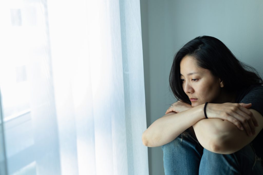 depressed woman sitting at window.10 Bible Verses to Hold on to When Life Feels Hard