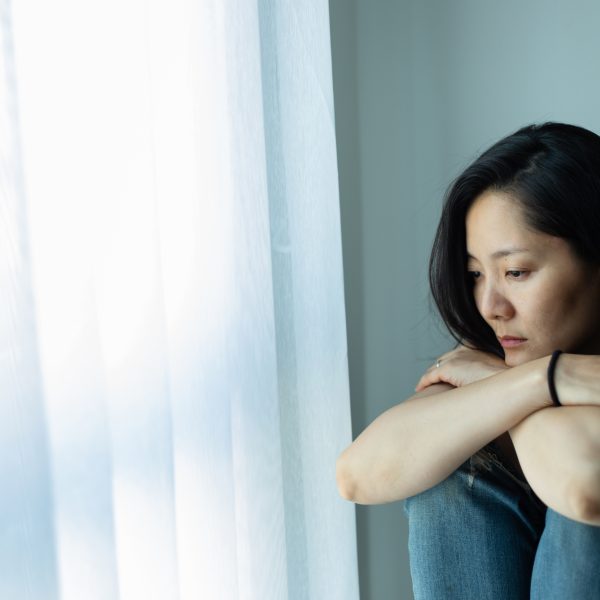 depressed woman sitting at window.10 Bible Verses to Hold on to When Life Feels Hard