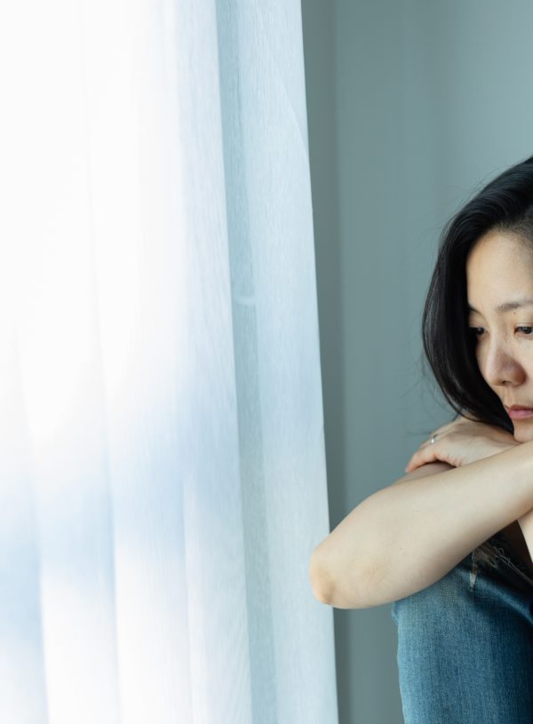 depressed woman sitting at window.10 Bible Verses to Hold on to When Life Feels Hard