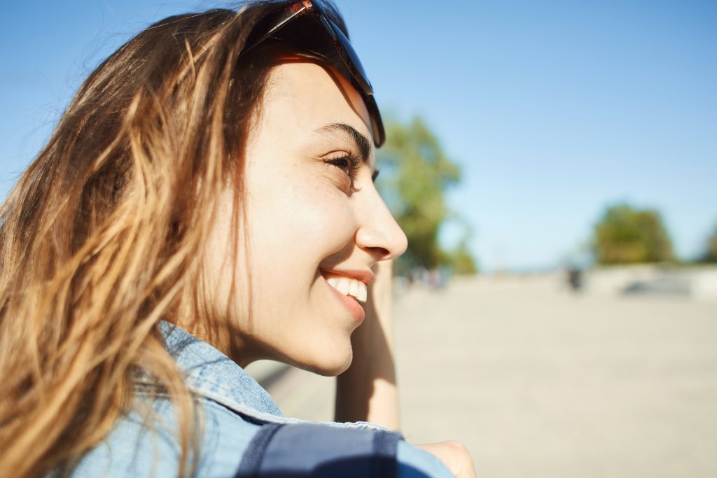 close up woman smiling in sunshine. 5 Unexpected Benefits of Doing God's Will Even Through Trials