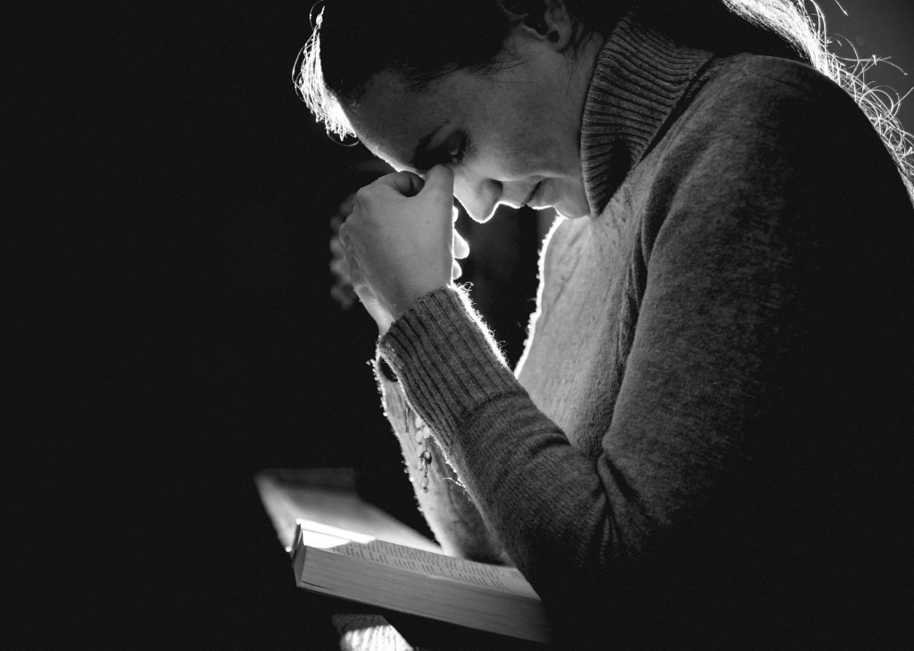 women bent over Bible in prayer. Prayers for Strength When You Feel Like Giving Up